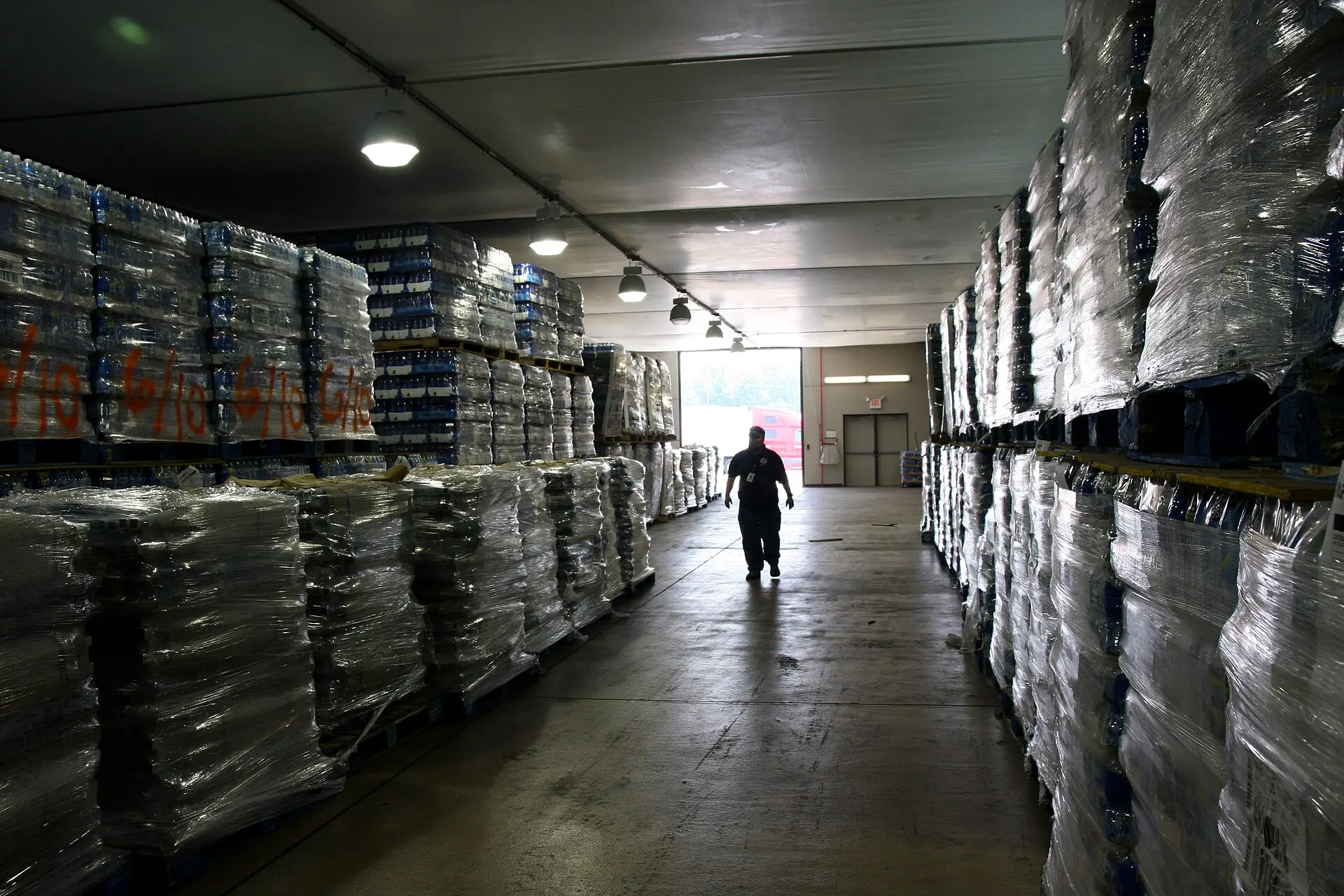 A long warehouse aisle of shrink-wrapped pallets